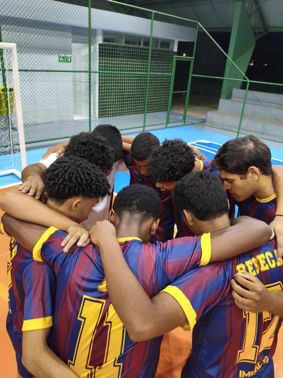Jogadores abraçados em uma roda de união na quadra